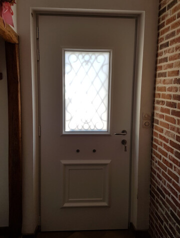 Porte beige à hublot losange, encadrement en brique