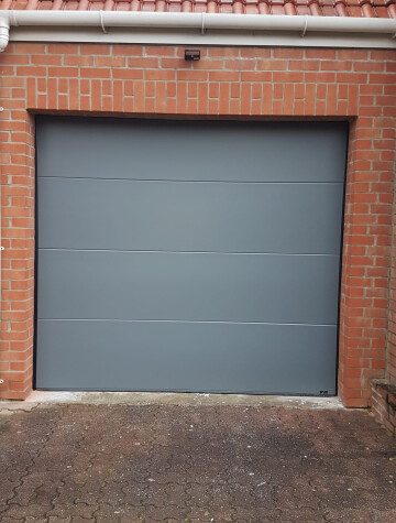 Porte de garage sectionnelle grise, accès pavé