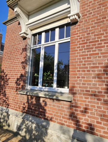 Fenêtre blanche sous balcon, façade en brique