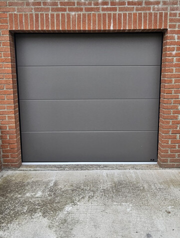 Porte de garage sectionnelle grise, façade en brique