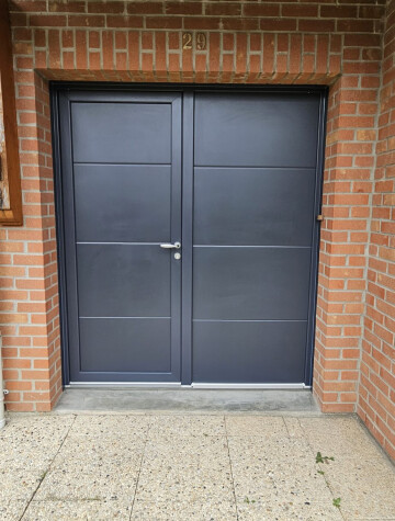 Porte d’entrée grise à deux vantaux, encadrement en brique