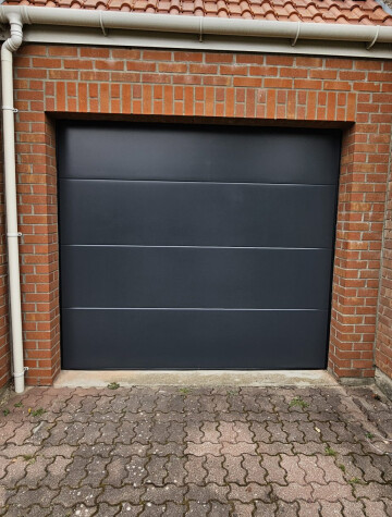 Porte de garage sectionnelle grise, accès pavé