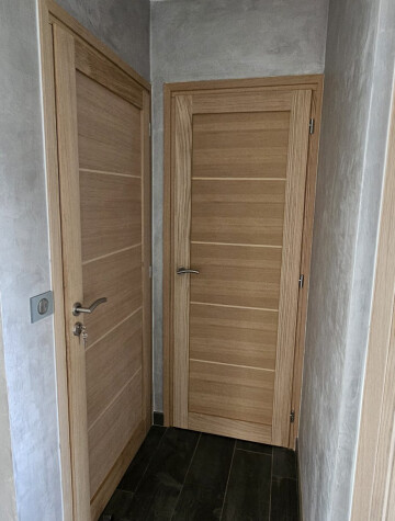 Porte intérieure bois clair ouvrant sur un couloir