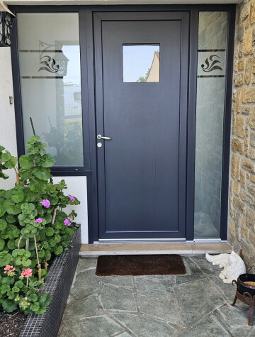Porte d’entrée grise avec vitrages, seuil en pierre