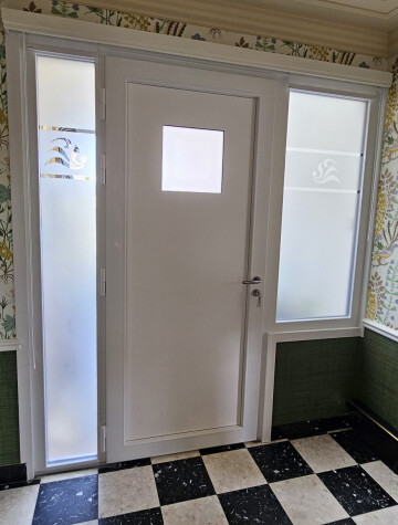 Porte d’entrée blanche vitrée, hall carrelé noir et blanc